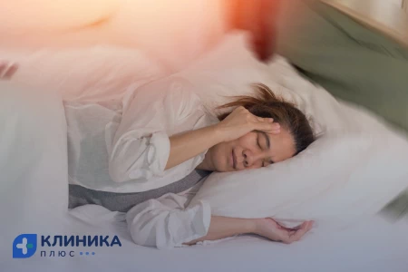 Девушка лежит в кровати и держится за голову
